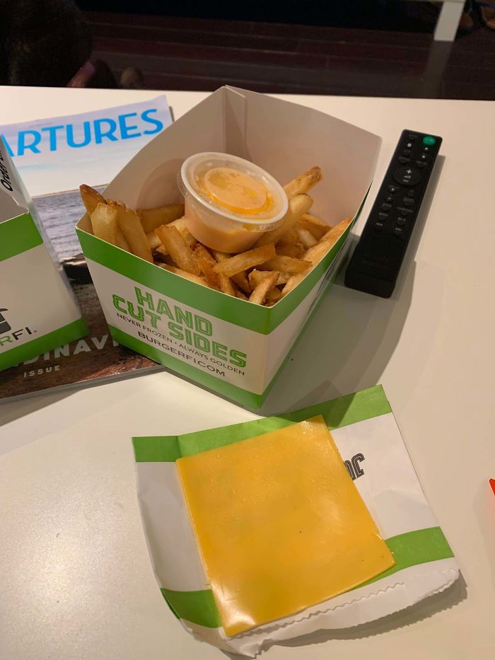 single slice of cheese on a napkin next to an order of french fries