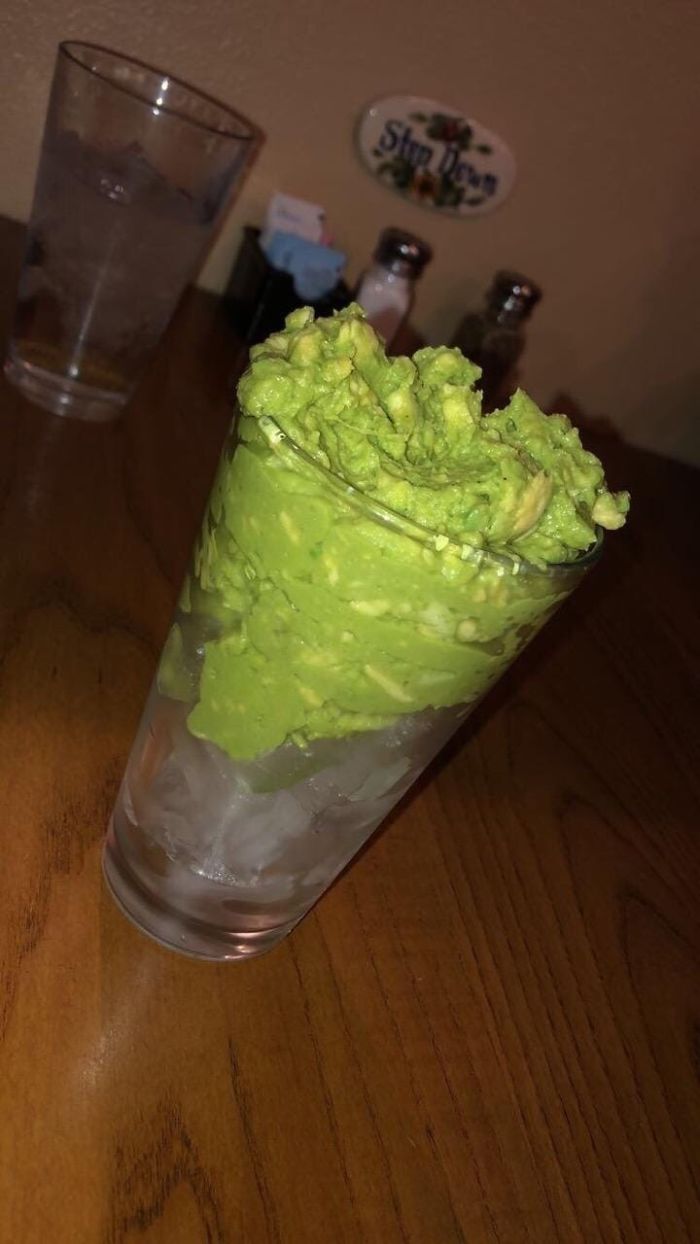 drinking glass filled with ice cubes and guacamole