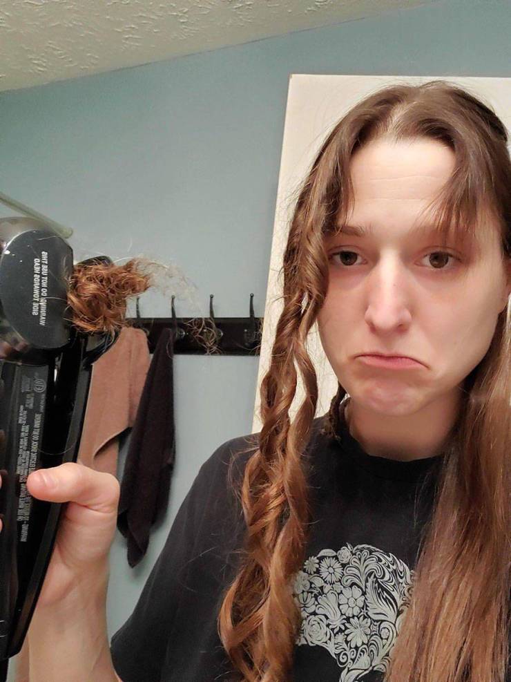 sad girl holding ripped out hair in curling iron