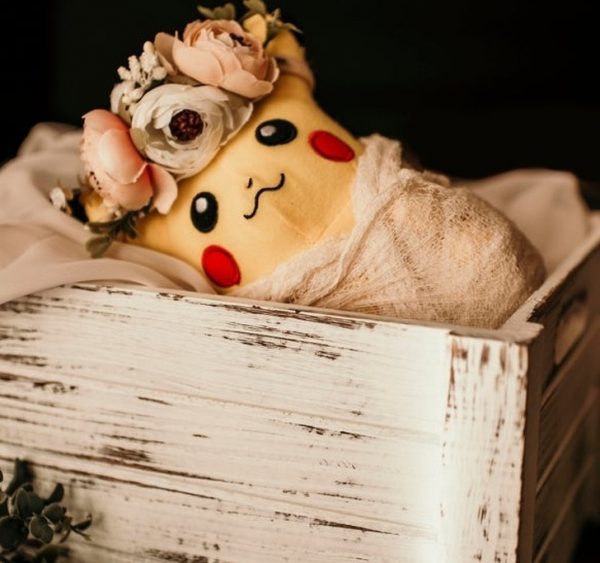 pikachu pokemon doll in a wooden basket with flowers on its head