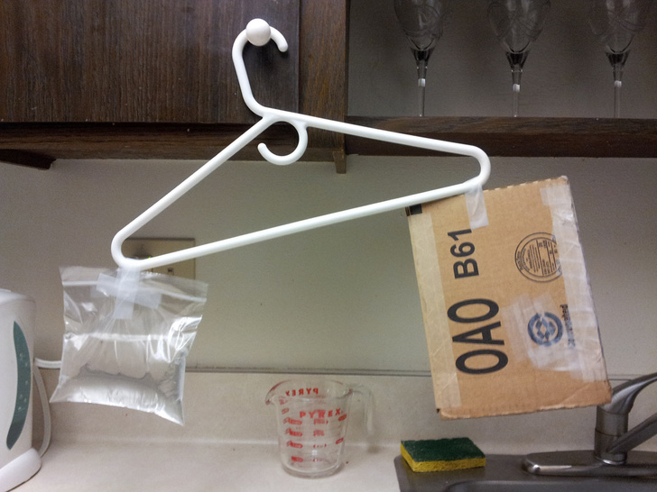 genius problem solvers - makeshift scale to measure weight of package with bag of water and clothes hanger