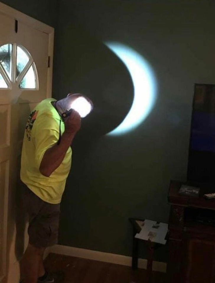 genius problem solvers - bald dad using a flashlight on his head to recreate lunar eclipse