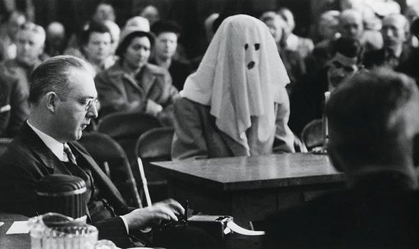 A witness with identity concealed gives evidence in court on narcotics traffic. Washington State, April 1952