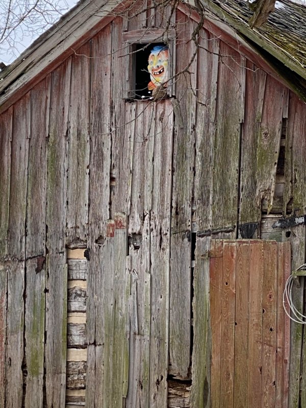 wooden barn with creepy clown face in top window