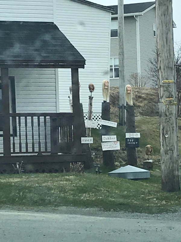 house with creepy doll heads on wooden stakes in the front yard