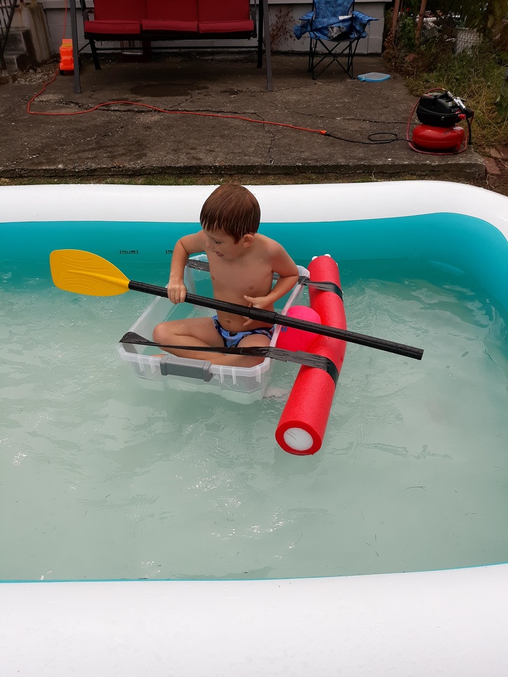 boy floating in pool in plastic tupperware boat