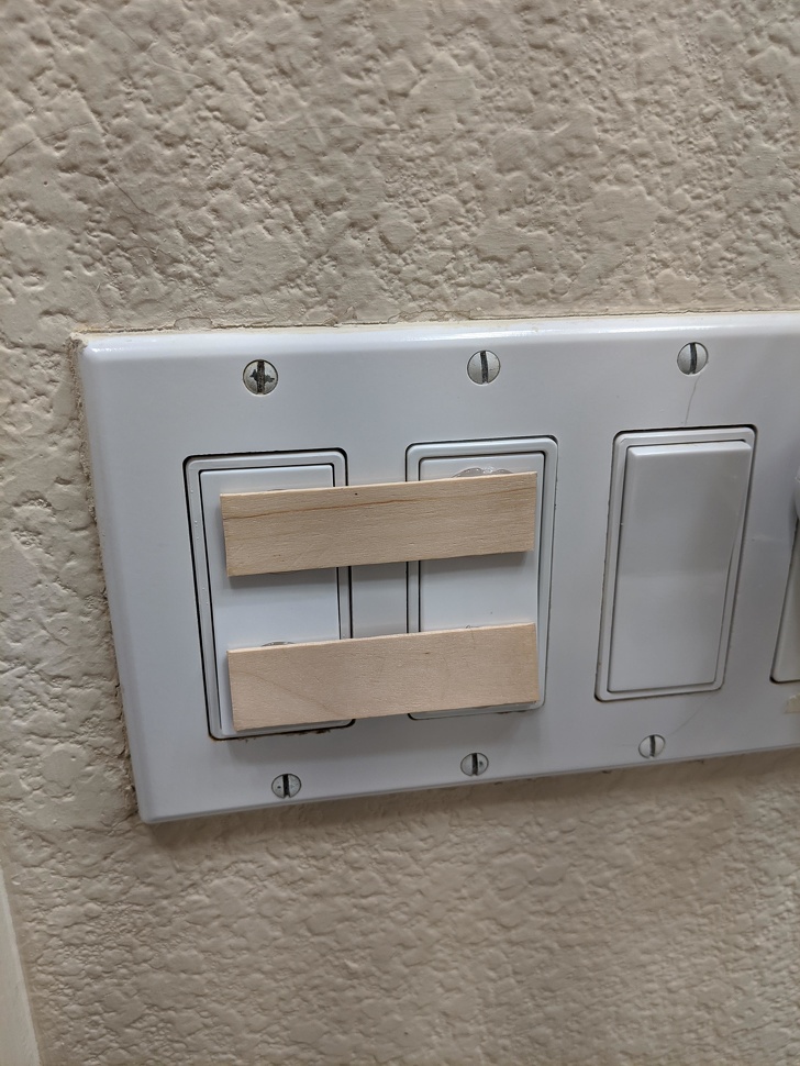 pieces of wood glued on light switches to make them easier to use
