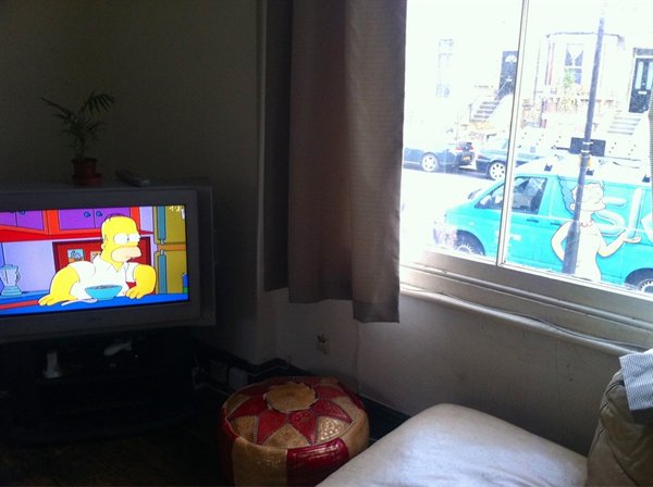 homer simpson on tv looking over at image of marge simpson in real life