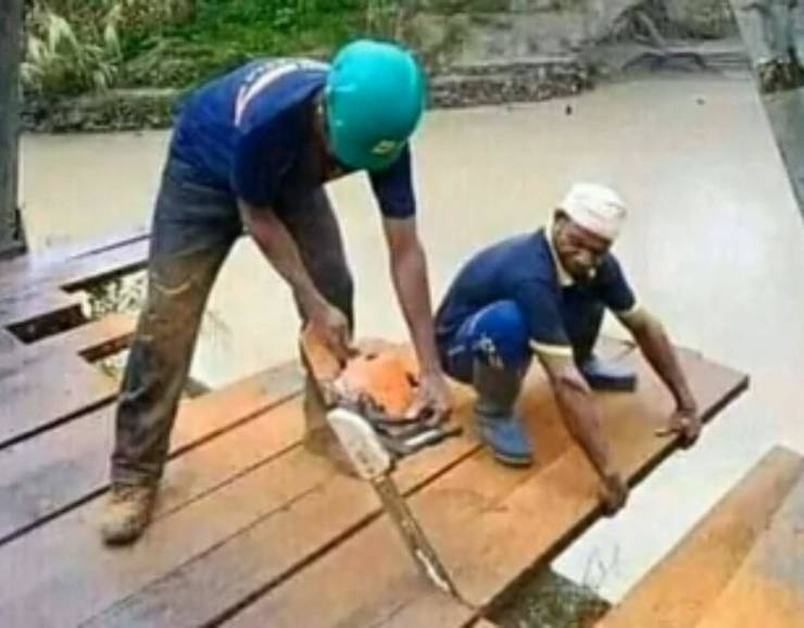 construction guy cutting board while is co-worker is standing on it
