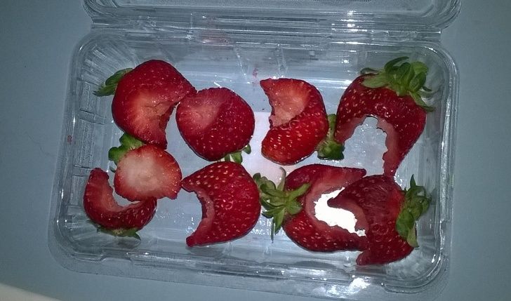 strawberries with bites taken out of them and put back in the container