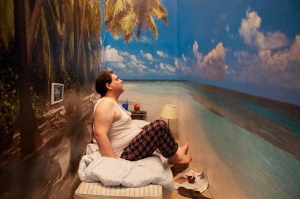 need a vacation bad guy sitting in weird cramped room with tropical wallpaper