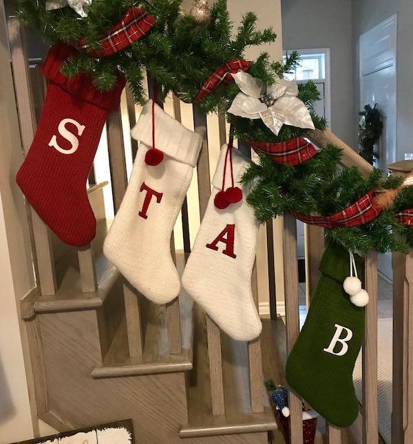 husband arranges monogrammed christmas stockings to spell STAB