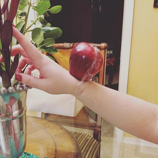woman has apple taped to her wrist as an apple watch