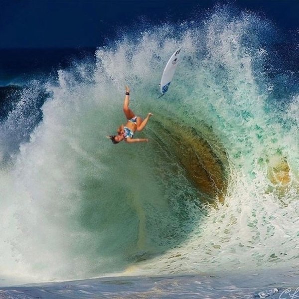 surfer falling off her board upside down in a wave