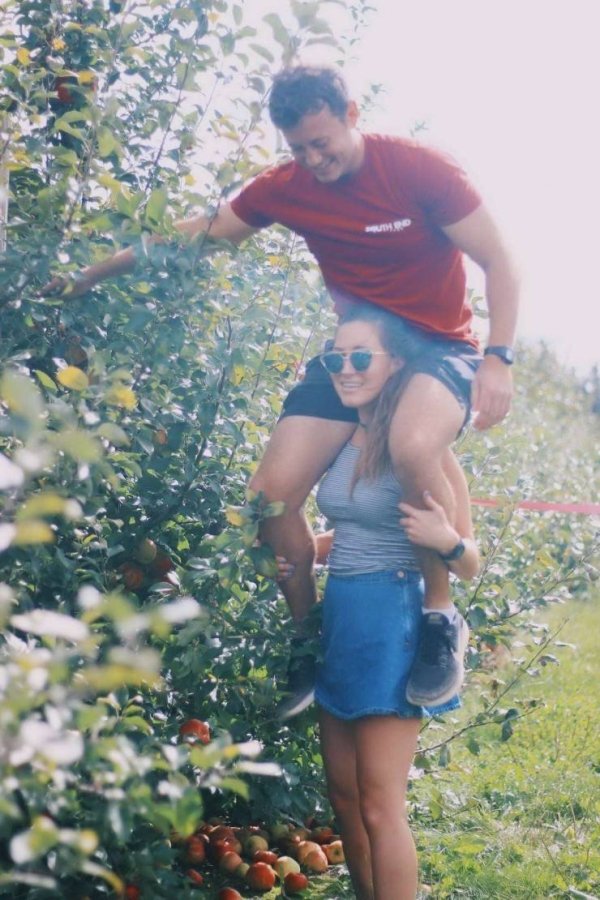 guy sitting on girl's shoulders picking berries