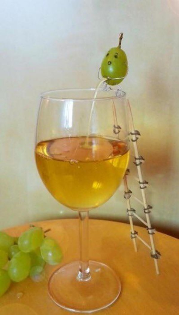 funny grape peeing into a wine glass