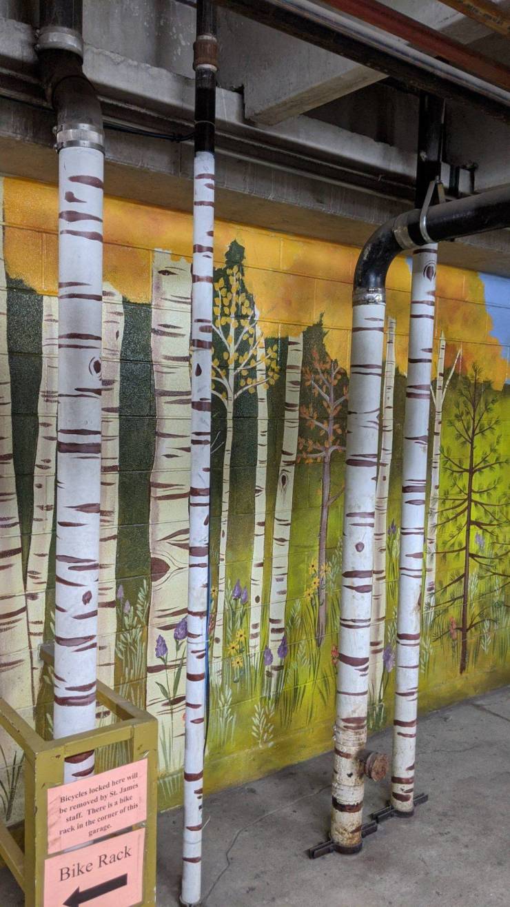 “This parking garage painted the utility pipes to match the tree mural behind it.”