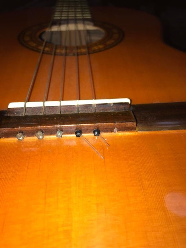What are the little black things used to bind the two right strings? They are on an old classical guitar.

<br/><br/><b>A:</b>  They’re just to keep you from having to tie the strings to the bridge. Pretty much every steel string uses these. It’s not as common with classical strings, but it’s not unheard of.
