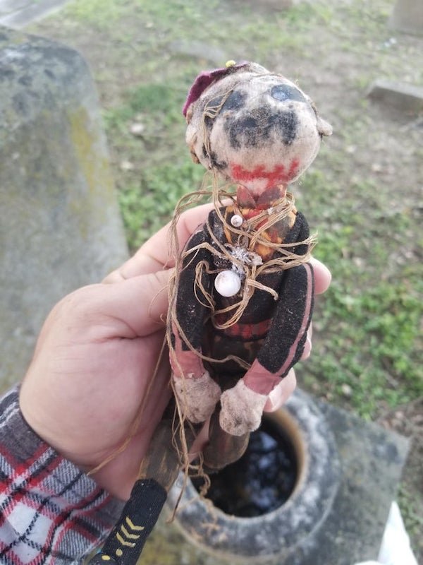 Found in a cemetary while geocaching. The doll was wrapped in the paper which was wrapped in the cloth cross and bound with twine. Overall very creepy.

<br/><br/><b>A:</b> I’m originally from Mexico and grew up hearing about different kinds of “brujeria” (witchcraft, not sure how to translate). Based on what I can make out of the written note, this is called an “amarre entierro”, a burial binding. Not sure if it’s tied up to Santeria or some other magic based religion, I’m not knowledgeable about this practices. I only know an entierro is used to curse a person and consists in making a doll representing that person with the damage you want to inflict upon them and burying it in a graveyard. Looks like the second photo of the note gives instructions on how to break the curse! It was too deteriorated to make out but I can read “to break the curse burial…you must find…3 crosses… and it will break the curse….you will never do it