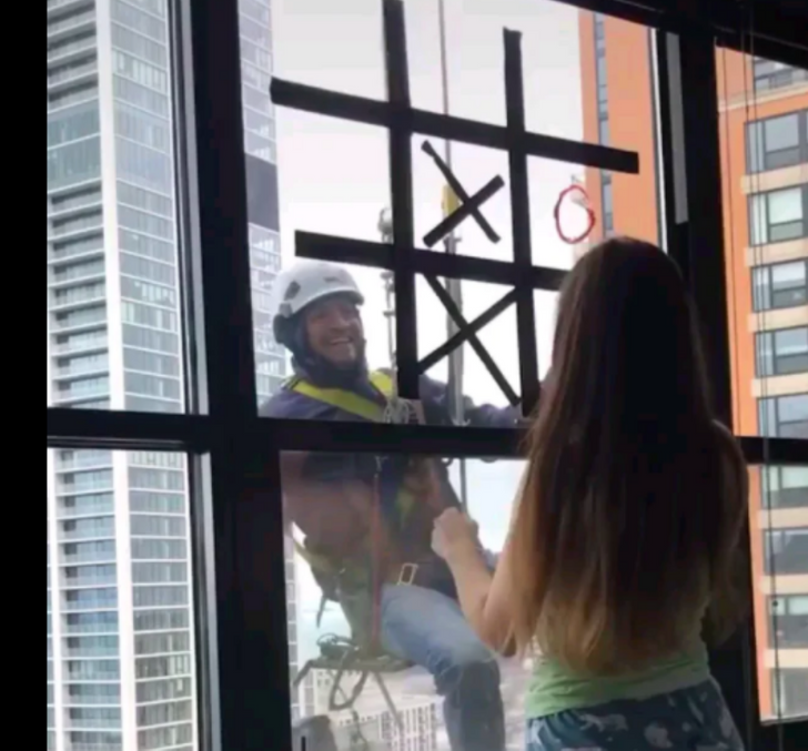 feel good pics - window washer playing game with girl in hospital