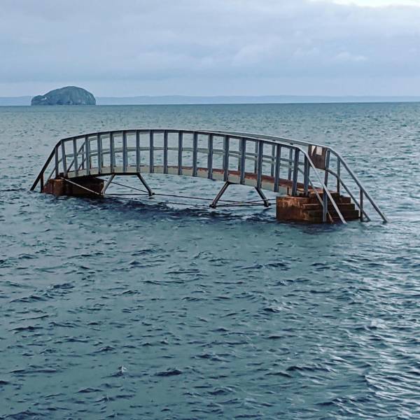 “This bridge to nowhere. When the tide is out, it allows beachgoers to cross a stream that cuts across the beach.”