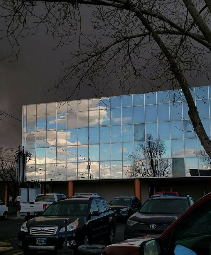 “Blue sky reflecting on neighboring building with storm behind it.”