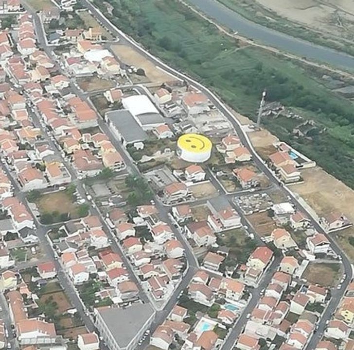 cool pics - building with a large yellow smiley face painted on top of it in spain