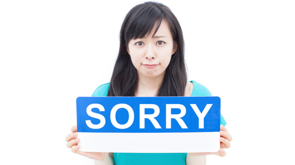 weird societal norms - woman holding sign that says sorry
