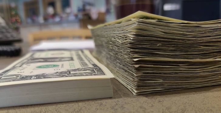 “A $100 stack of new, uncirculated 1-dollar-bills next to a $100 stack of used, circulated 1-dollar-bills”