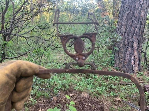 Hanger like thing found buried on my land.

A: It’s a Polaroid vintage auto sun visor frame. 1940s. There was a tinted plastic screen held in the curved frame.