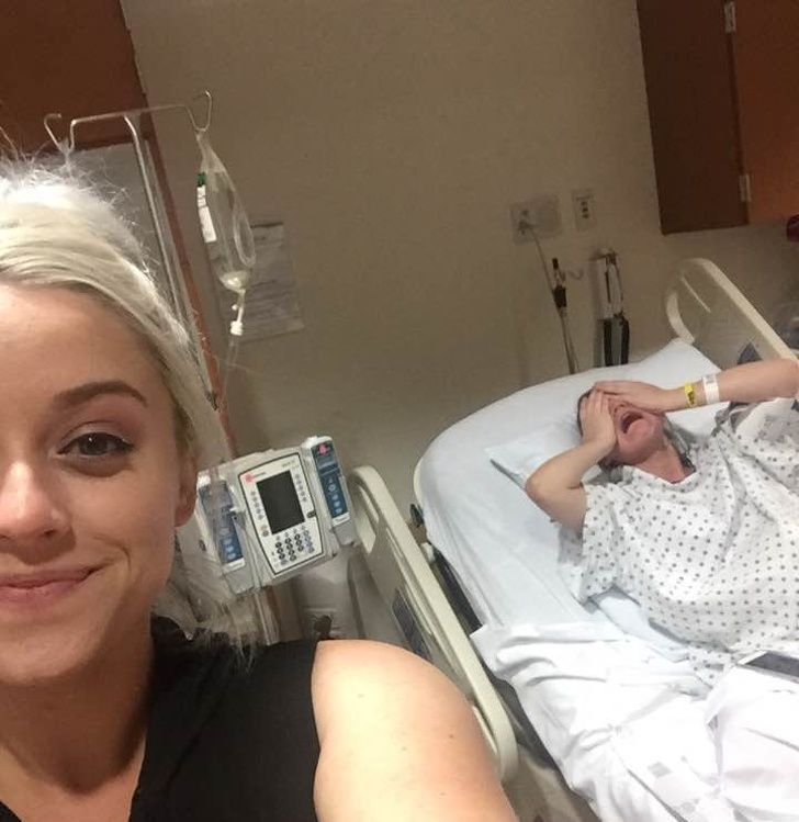 funny sibling pics - woman takes selfie in hospital while sister is giving birth in the background