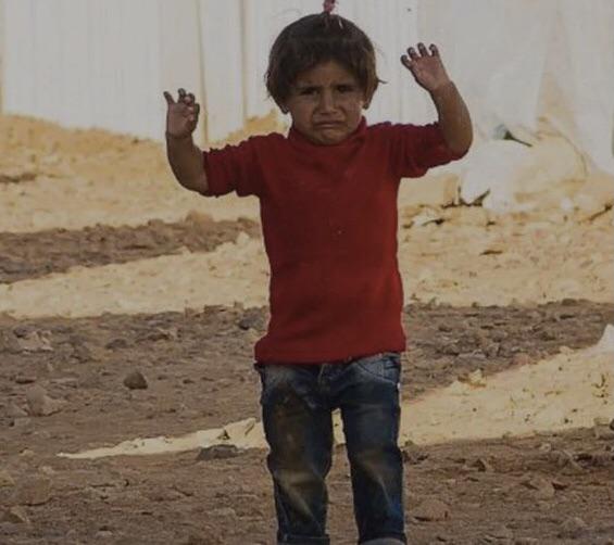A Syrian child mistakes a camera, held by a member of the Red Cross, for a gun