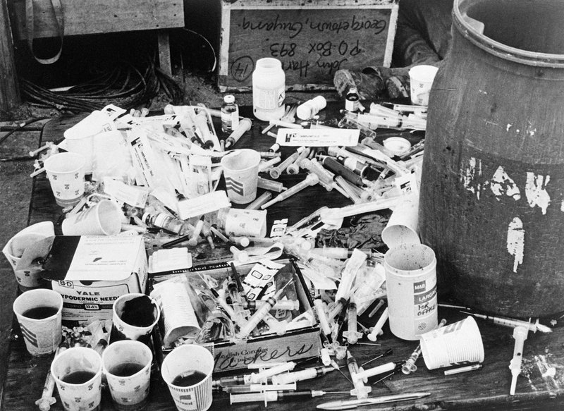 A table showing the vat, cups, and syringes full of grape Flavor Aid, poisoned with Valium, chloral hydrate, cyanide and Phenergan, that would take the lives of 900+ people in the Jonestown massacre, 1978