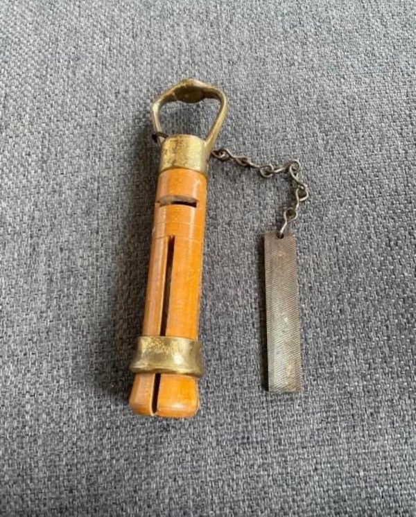 What is this wooden and metal vintage thing?

A: It is a snooker cue tipper. The cue is places into the open end to straighten and shape the tip and the file is inserted into the open horizontal slot to make the tip perpendicular. Kinda like a pencil sharpener for a snooker cue.