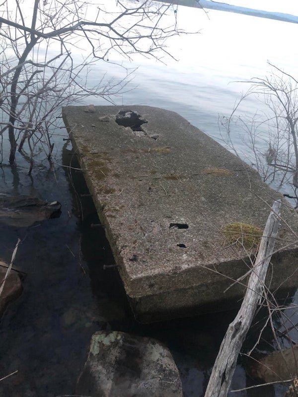 Coffin sized concrete container with lid. It has rebar sticking out the sides of the lid.

A: It’s part of a jetty of some sort. Those bolts look like they could have secured a wooden beam to the side to form a protective edge.