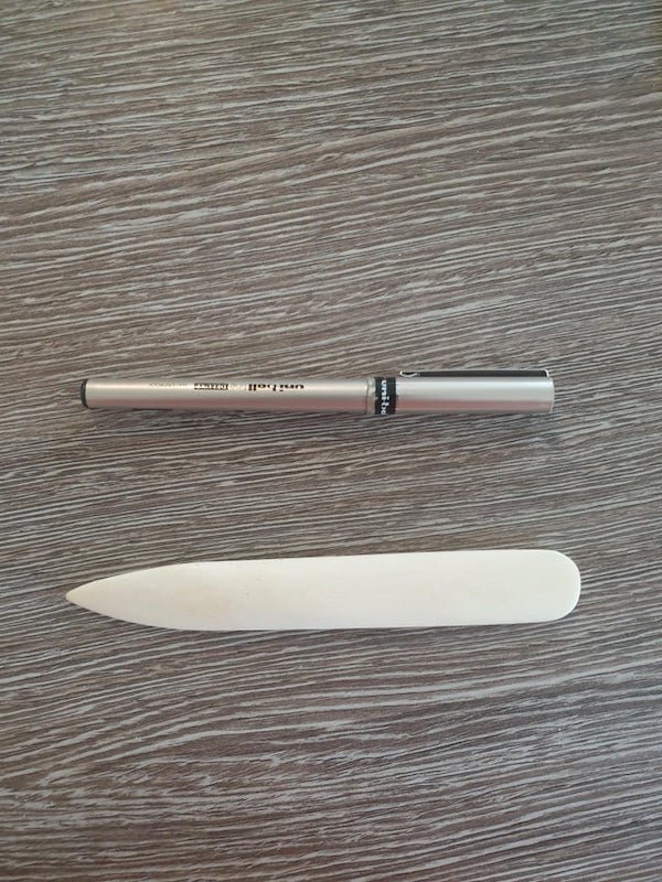 Strong white ivory pen sized, flat object. Slightly curved. We are Scottish so I thought a kilt thing but husband disagrees, I am a knitter so he thought a knitting thing but I disagree. Feels strong like fake ivory.

A: A folding bone. Certainly looks the part.