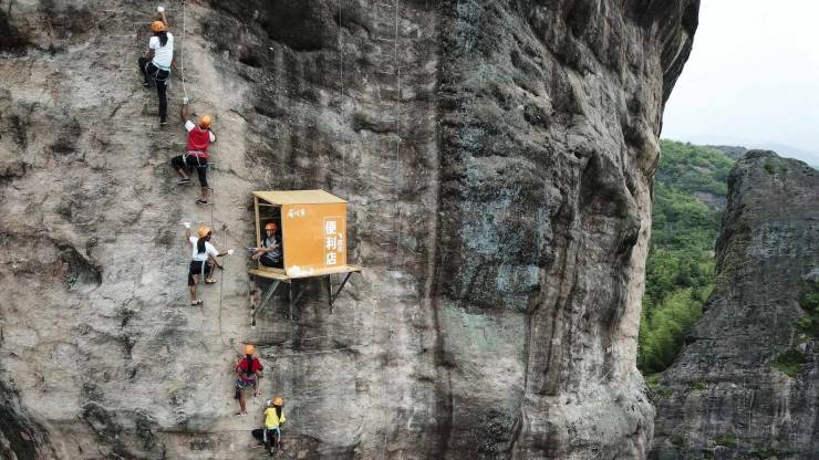 “A convenience store hung over a cliff 100 meters above the ground in Central China. It offers water and snacks to climbers.”