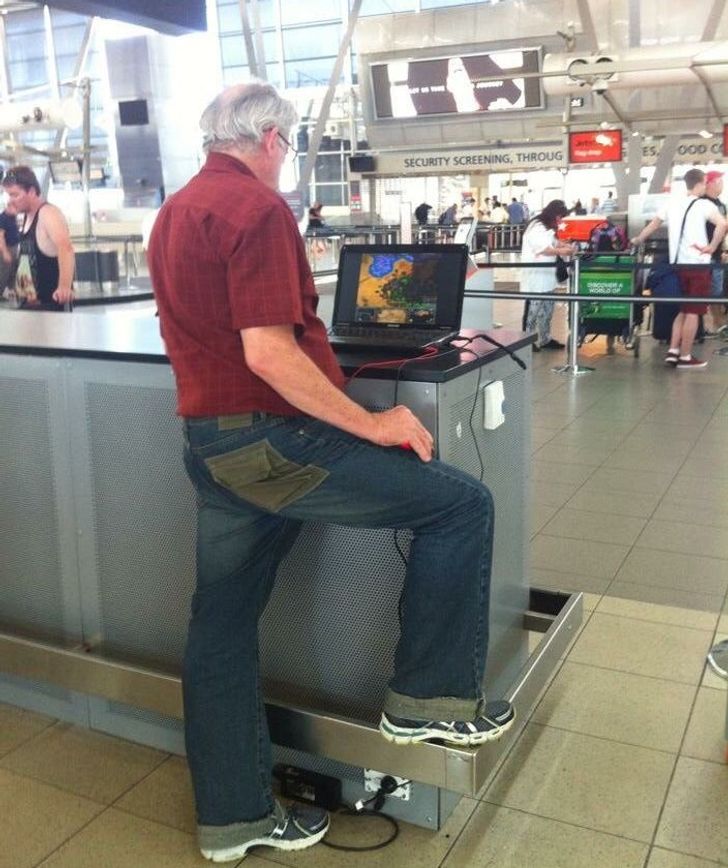 funny airport pics -- man playing computer games at airport using his knee as mousepad