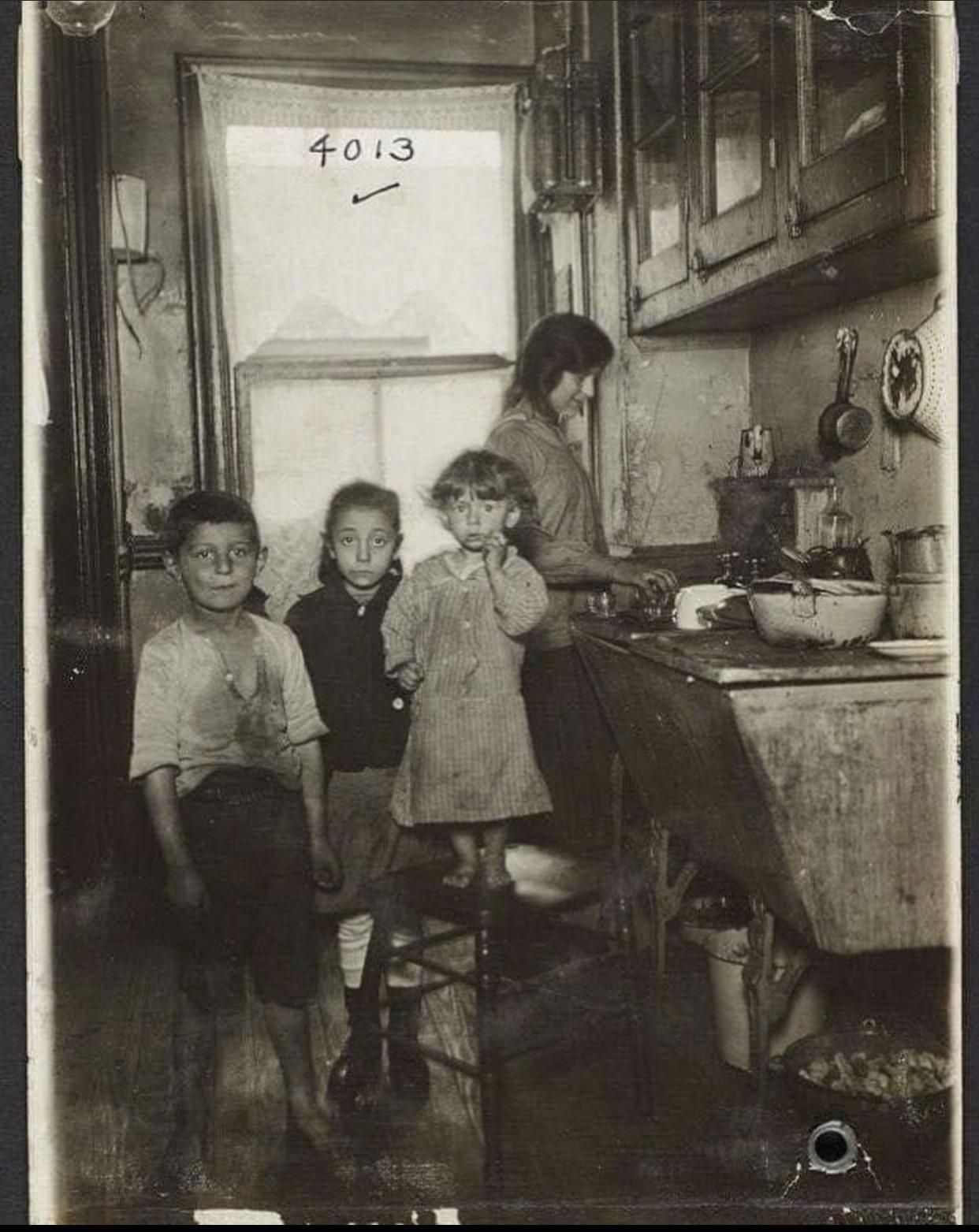 A mother and her three children in their tenements kitchen, Lower East Side NYC, 1915