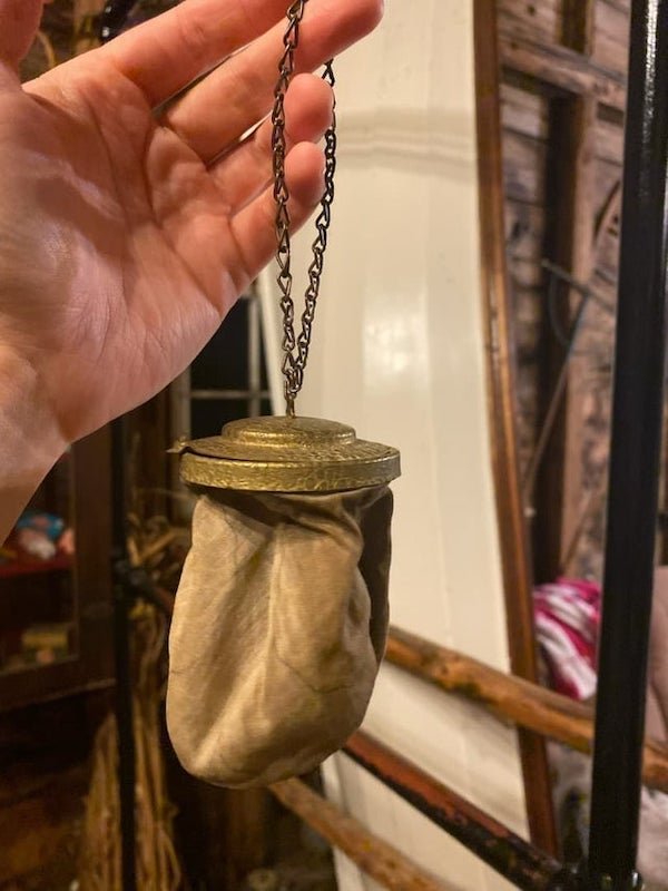 WITT found in an old barn with a bunch of Christian religious items in Nova Scotia, Canada? The lid inside holds a mirror and snaps closed to the rim of the bag. The bag appears to be burlap inside and a different material on the outside, is blue inside and has no smell.

A: The mirror, and style of metal top with fabric bag attached, would suggest it’s a lady’s reticule (a tiny handbag popular in the 19th-early 20th century).