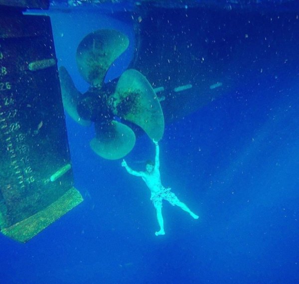 Here’s a swimmer holding on to a giant underwater boat propeller.