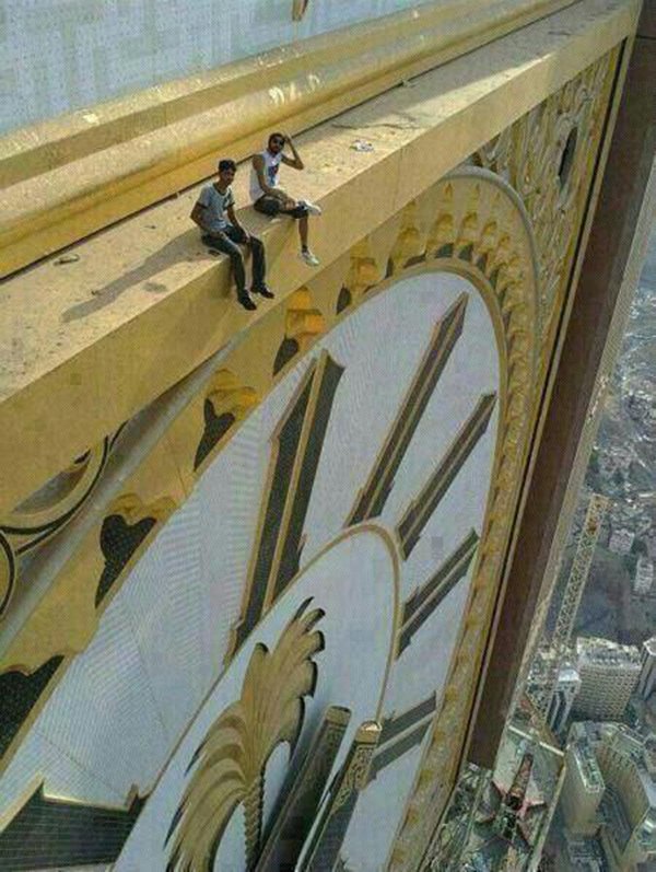 Two people sitting on the Abraj Al Bait clocktower in Mecca.