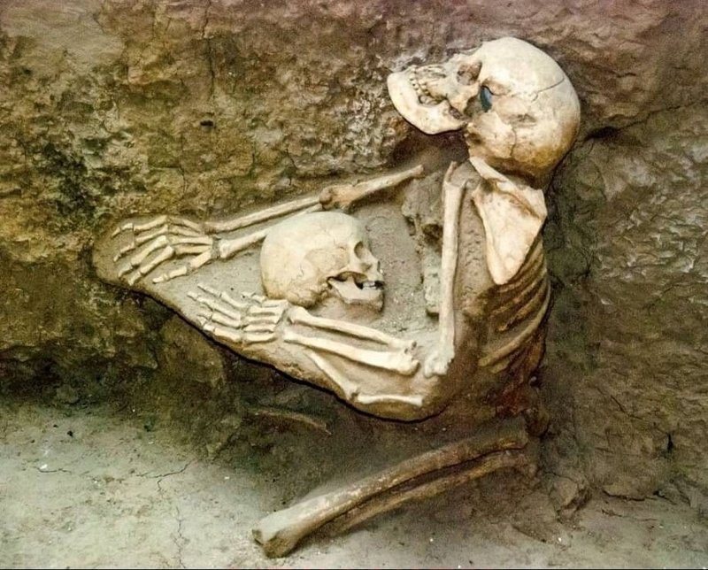Two skeletons , a woman clutching a child to her breast , preserved in a mudflow in tibet for 4000 years