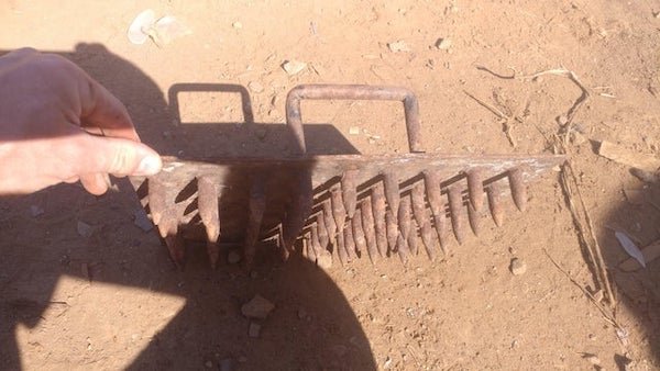 Found in a pile of scrap steel. About 1 foot across. Two handles and covered in spikes.

A: It looks like a dibble board for making small holes to plant seeds in soil/seed trays, not seen one made from metal before though.