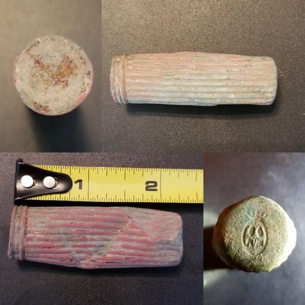 Weird metal tube (now dented) found metal detecting in SE Iowa on a farmstead that stood from the 1890s-1960s. Seems to be made of copper, found 4″ down, and has a bat-like symbol on one end. It’s closed on both ends and feels hollow.

A: Looks like old lipstick