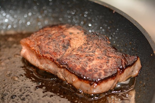 Only flip your steak once during cooking.

It all comes down to the temperature of your pan. Keep it nice and hot, and you can flip multiple times for an even sear from edge to edge.