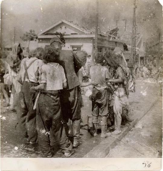 Dazed survivors huddle together in the street ten minutes after the atomic bomb was dropped on their city, Hiroshima. August 6, 1945.