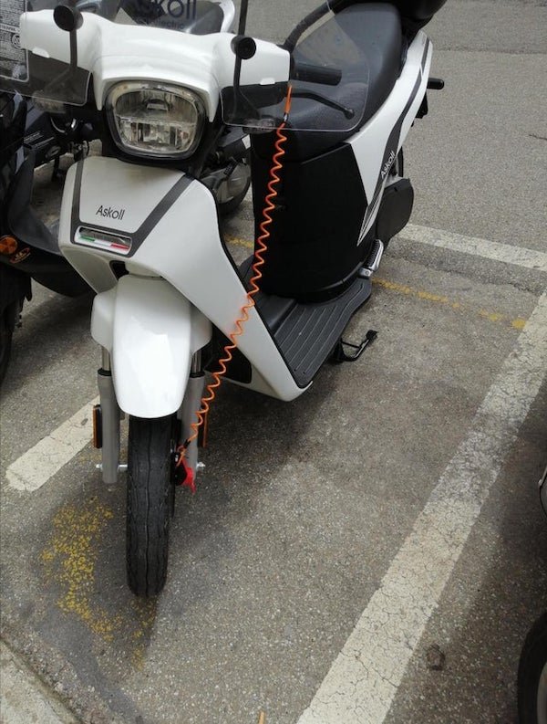 What’s the orange thing on this motorbike? It’s attached to the front brake and hooked to the handle

A: Disc locks are quite small and either easily forgotten by the owner or not noticed by a potential thief. If you move a bike with the disk lock attached you can easily damage the brakes. The cable hooks round the disc lock and over one of the levers as a reminder to the owner that it needs removing before they ride off. Also it indicates to anyone trying to steal it there is a lock on the wheel.