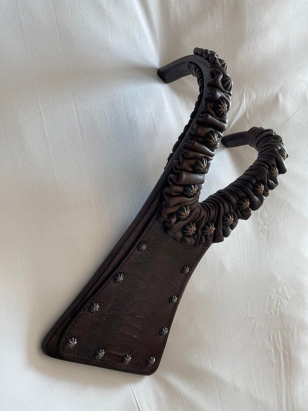 It is about 12 inches long, made of wood, and wrapped in leather. Maybe something to do with boots?

A: It’s a boot jack