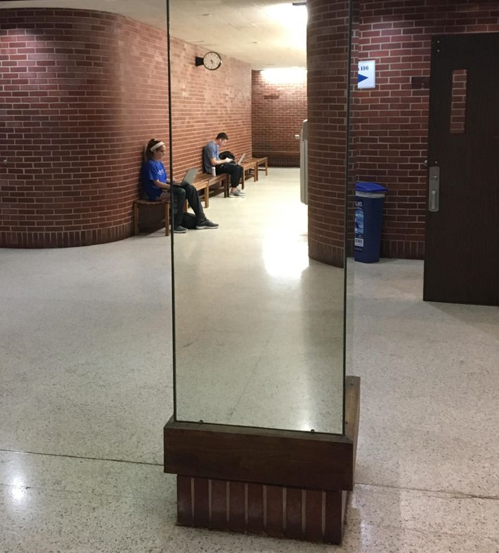 “This mirror column in a building on my college campus seems see-through when looking down the hallways.”